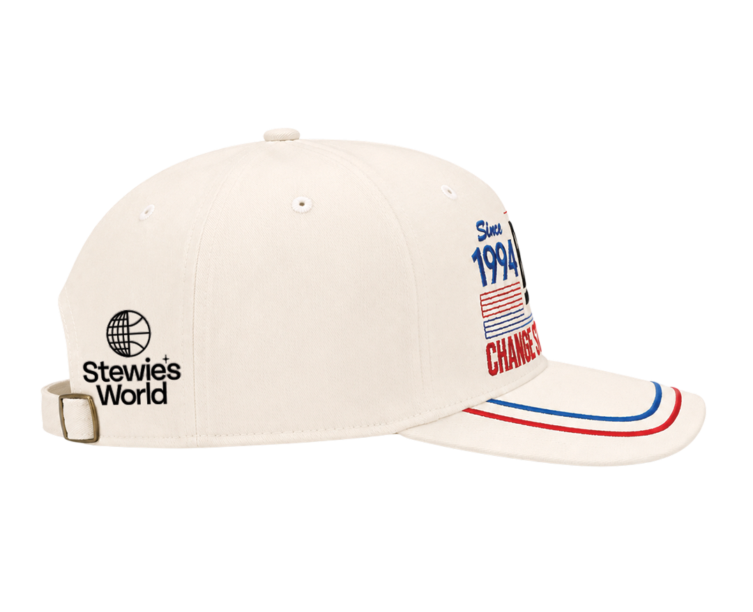 An off-white baseball cap with 'Stewie's World' embroidered on the side and patriotic red, white, and blue graphics on the brim, shown against a plain white background.