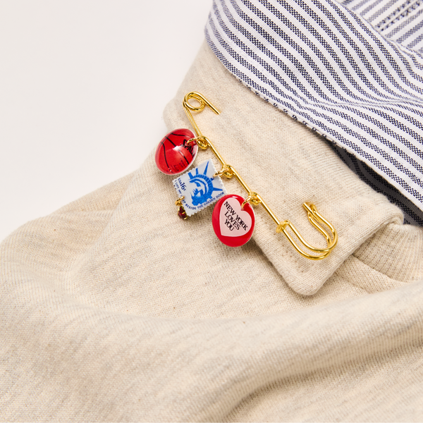 Close-up of a XL Safety Pin on a beige garment with a striped shirt in the background.